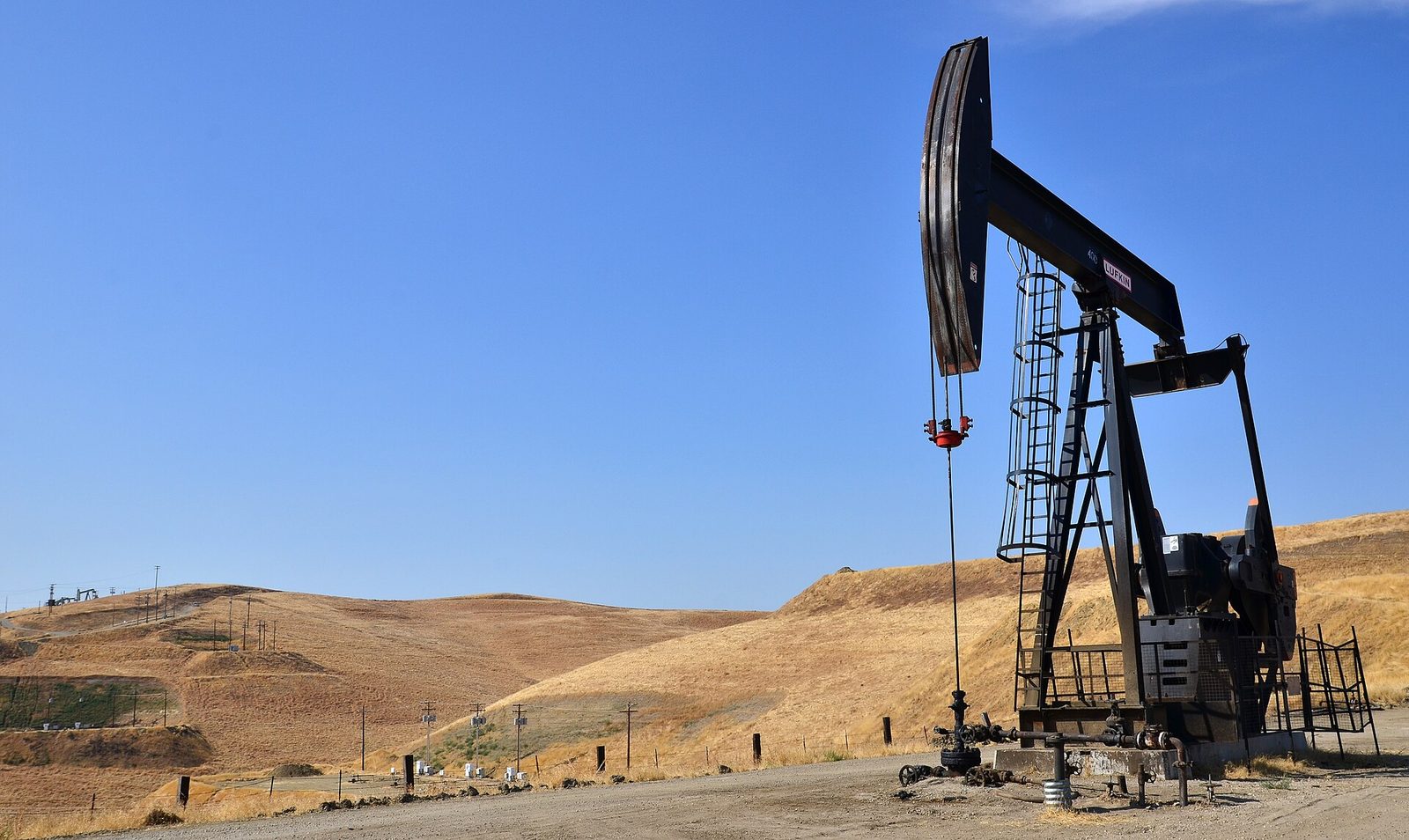 An oil pumpjack on a federal oil and gas lease managed by the Bureau of Land Management among dry golden hills in California.