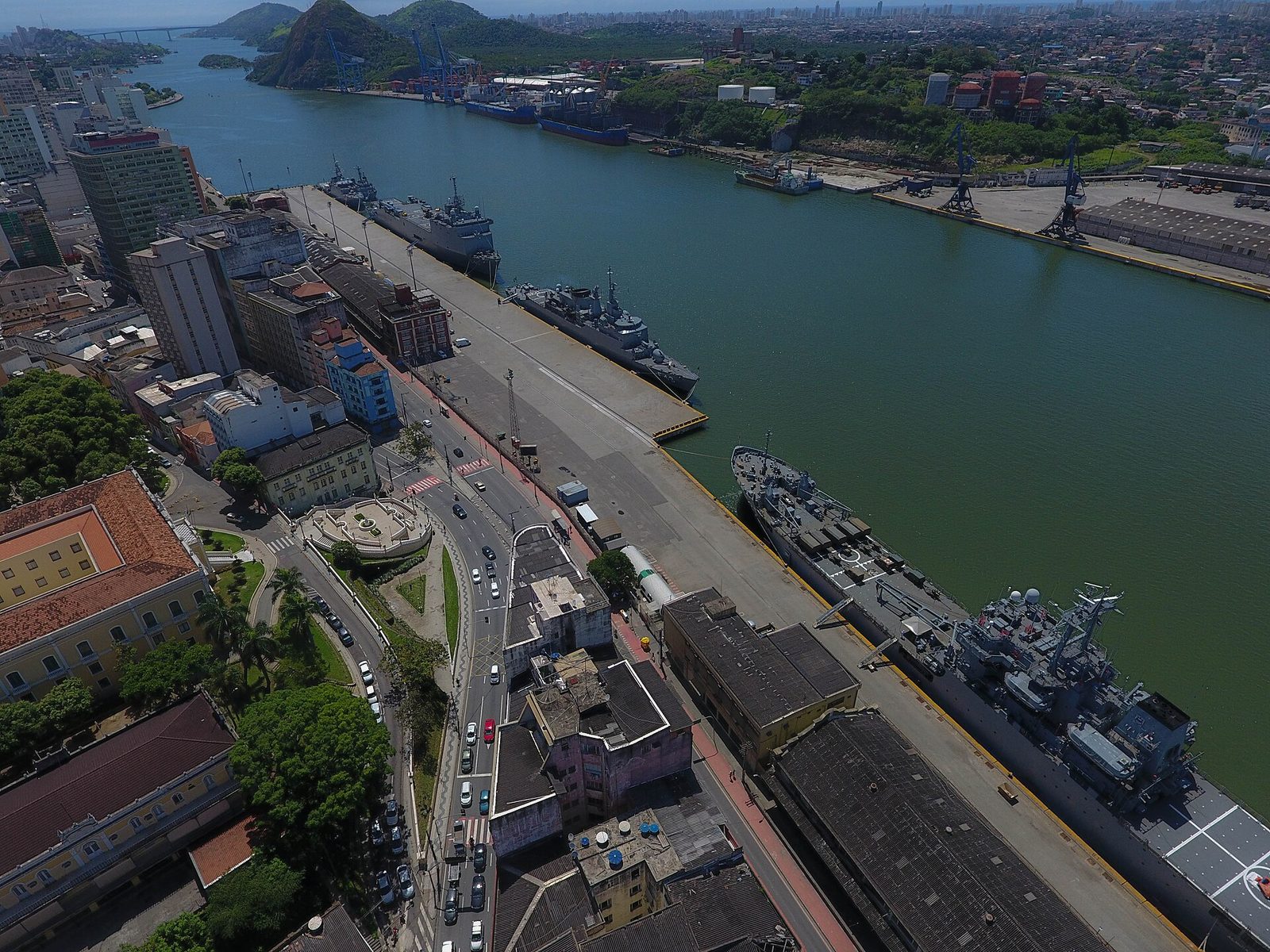 Aerial view of a Brazilian harbor district with port infrastructure, cranes, ships, and a waterway through a coastal city.