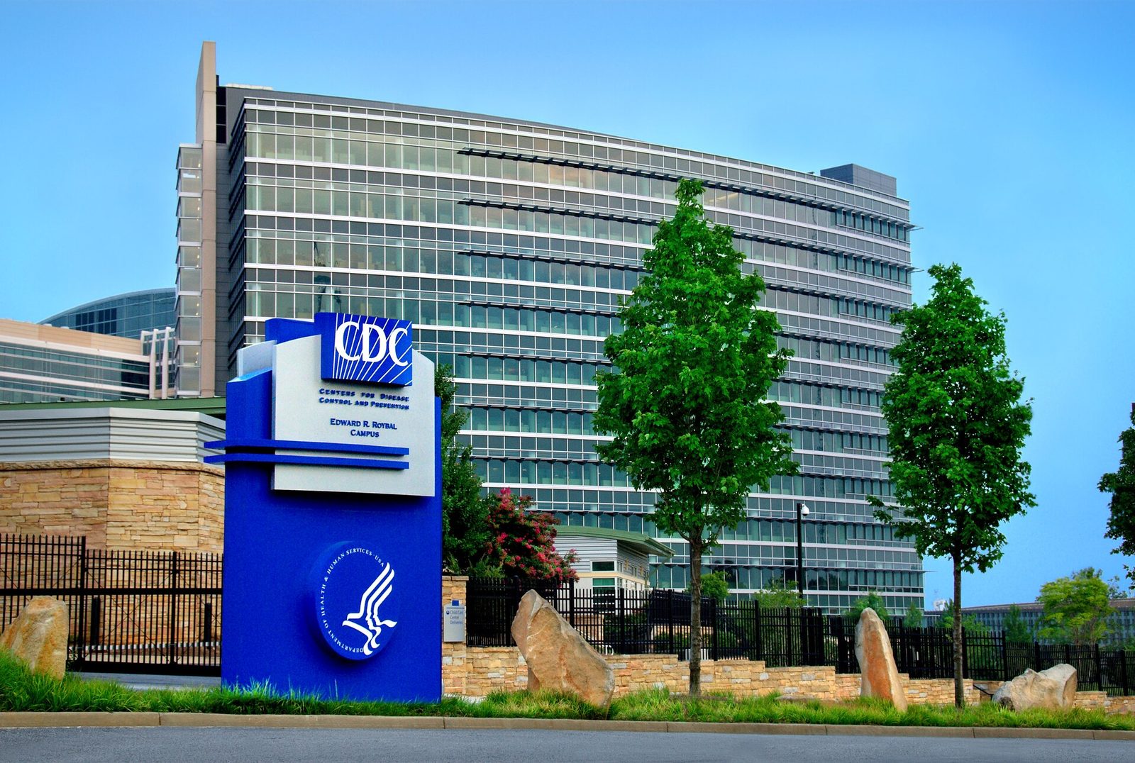 The CDC sign in front of a glass office tower on the Centers for Disease Control and Prevention Roybal campus in Atlanta.