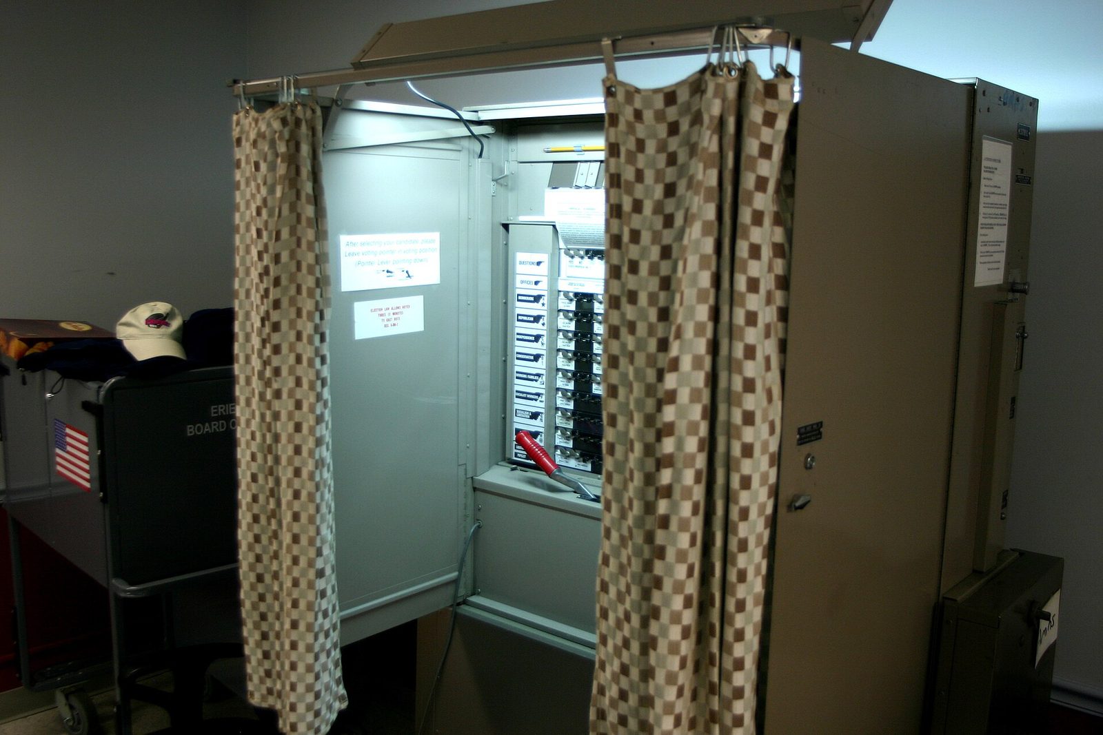 An American curtained voting booth with a lever voting machine inside.