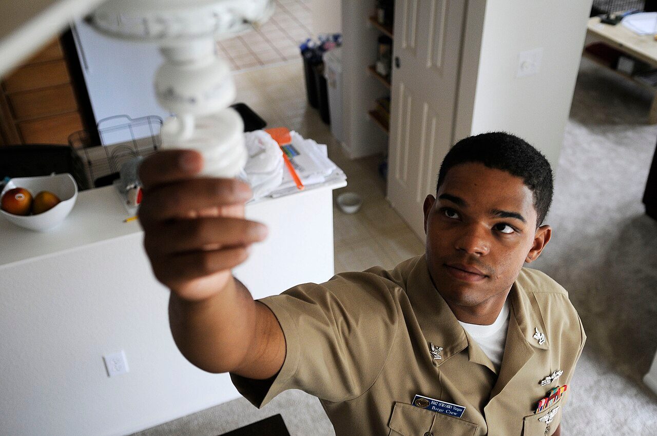 A U.S. Navy sailor installs high-efficiency light bulbs as part of an energy-conservation initiative, Hawaii, 2011.