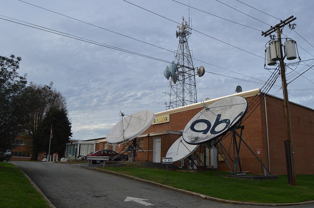 Exterior of an ABC-affiliate television station (WSET-TV) with satellite dishes and a broadcast tower.